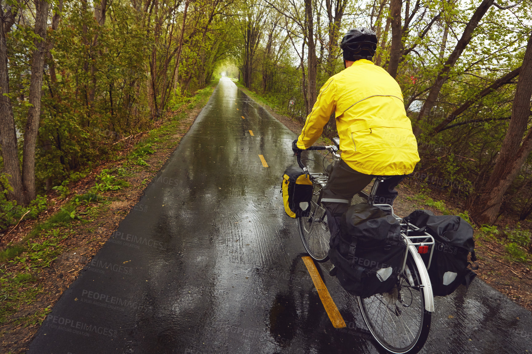 Buy stock photo Rearview shot of a male cyclist enjoying a bike ride on a wet winter's morning