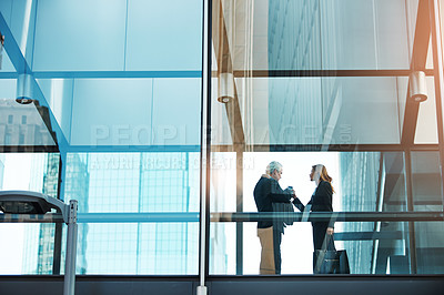 Buy stock photo Shot of a businessman and businesswoman having a discussion in a modern glass office