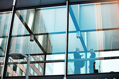 Buy stock photo Shot of a businessman and businesswoman having a discussion in a modern glass office