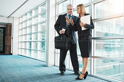 Buy stock photo Shot of a businessman and businesswoman using a mobile phone together in a modern office