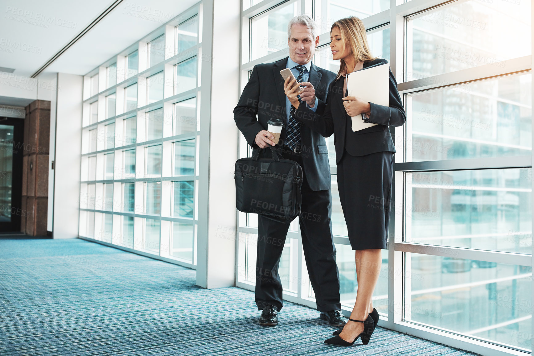 Buy stock photo Shot of a businessman and businesswoman using a mobile phone together in a modern office