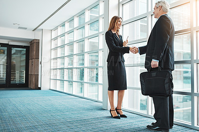 Buy stock photo Shot of a businessman and businesswoman shaking hands in a modern office