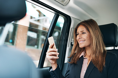 Buy stock photo Shot of a mature businesswoman using a mobile phone in the back seat of a car