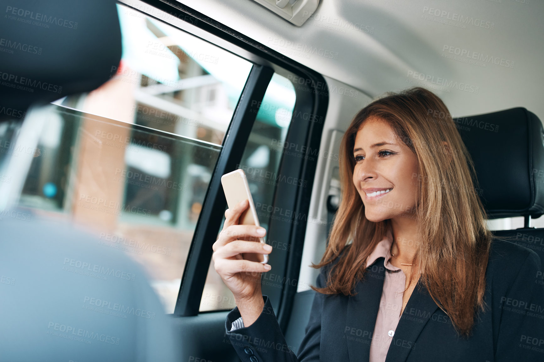 Buy stock photo Shot of a mature businesswoman using a mobile phone in the back seat of a car