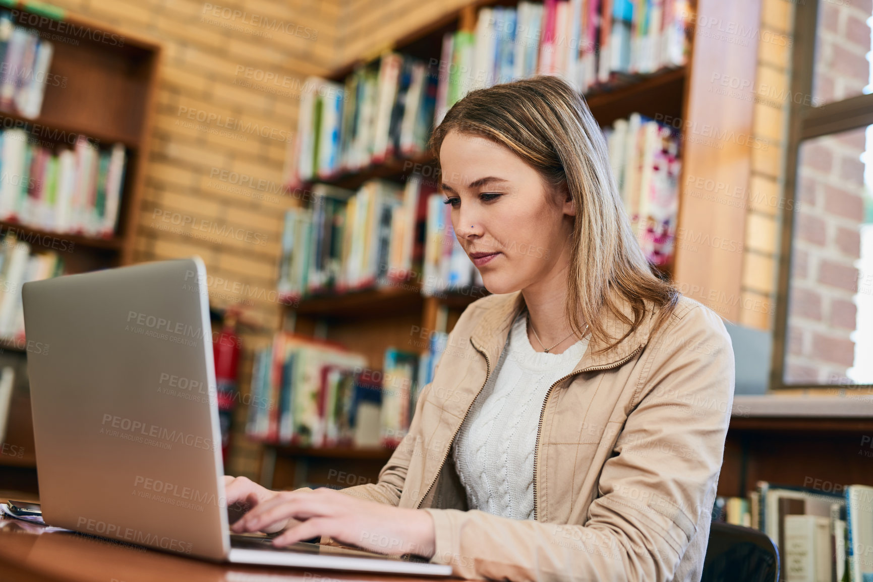 Buy stock photo Cropped shot of a university student doing some research on a laptop