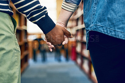 Buy stock photo Cropped shot of a couple holding hands as they walk through a library