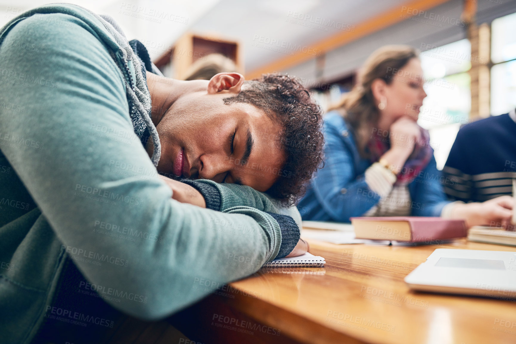 Buy stock photo Man, student and sleep at college with group, burnout and tired with books, tech and education in library. Person, fatigue and exhausted with studying, learning and development in hall at university