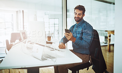 Buy stock photo Cropped shot of a handsome young businessman checking his cellphone while sitting in the office