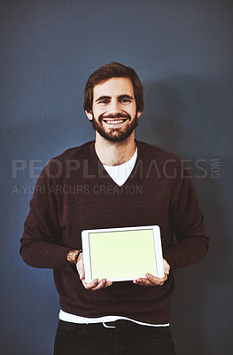 Buy stock photo Studio portrait of a young man holding a digital tablet against a grey background