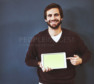 Buy stock photo Studio portrait of a young man pointing to a digital tablet against a grey background