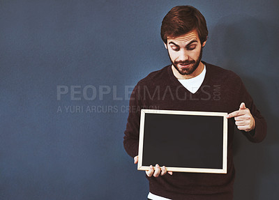 Buy stock photo Studio shot of a young man pointing to a blackboard against a grey background