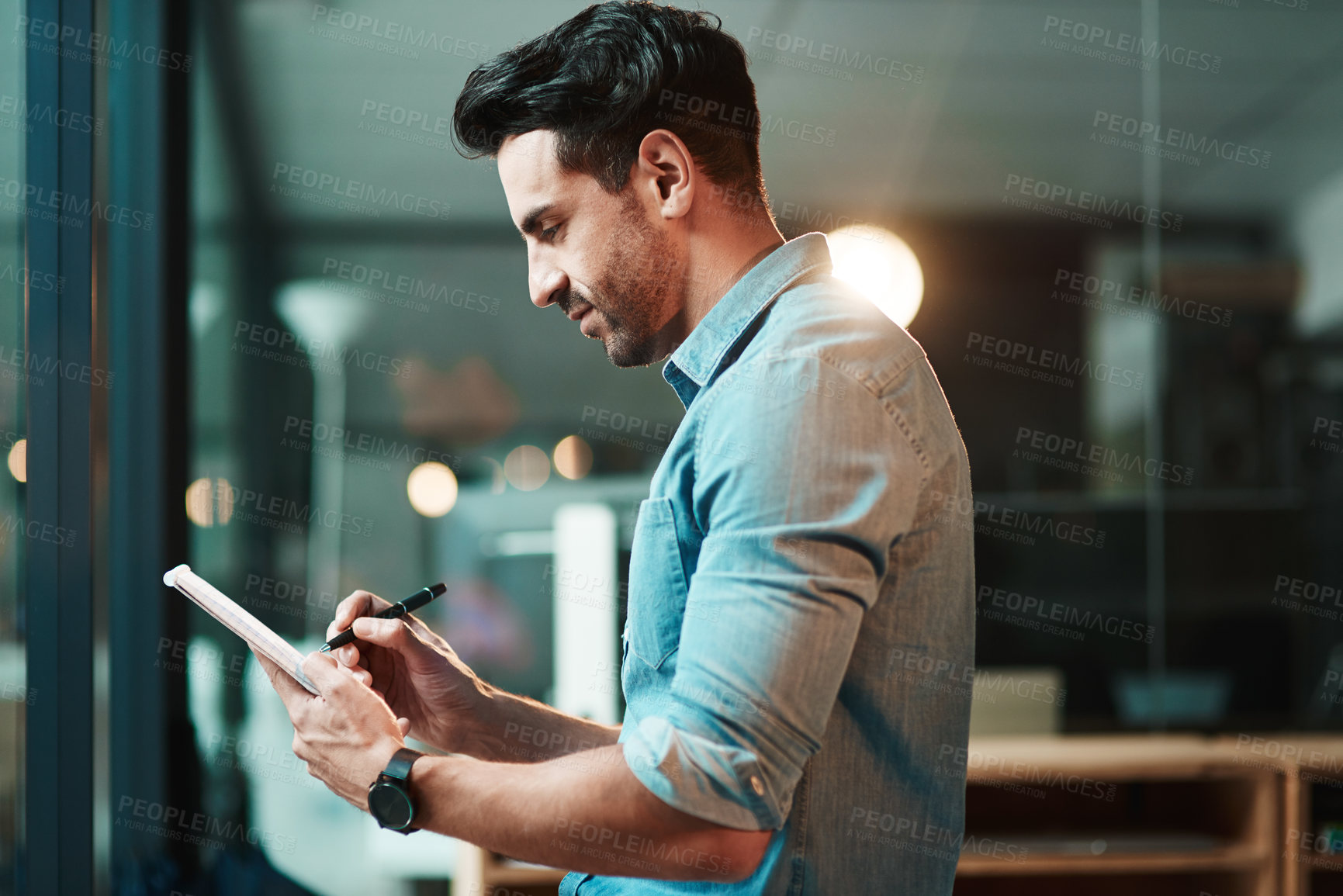 Buy stock photo Shot of a young businessman using a digital tablet in a modern office