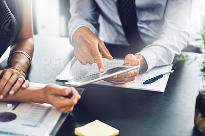 Buy stock photo High angle shot of two unrecognizable businesspeople looking at a digital tablet in their office