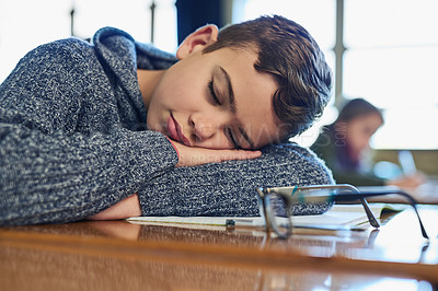 Buy stock photo Shot of an elementary school boy sleeping on his desk in class