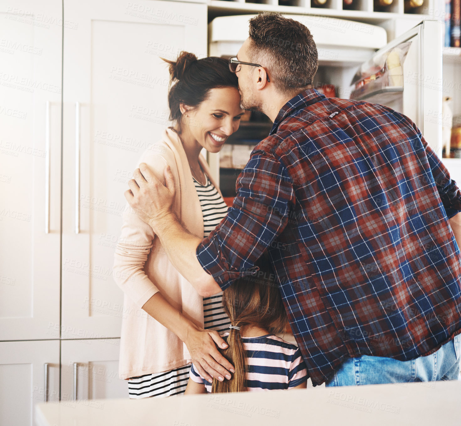 Buy stock photo Shot of a husband lovingly kissing his pregnant wife in the kitchen