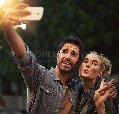 Buy stock photo Shot of a young couple taking a selfie in the city