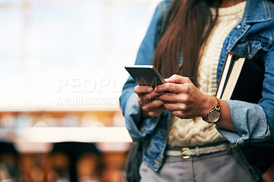 Buy stock photo Closeup shot of a university student texting on her cellphone in the library at campus