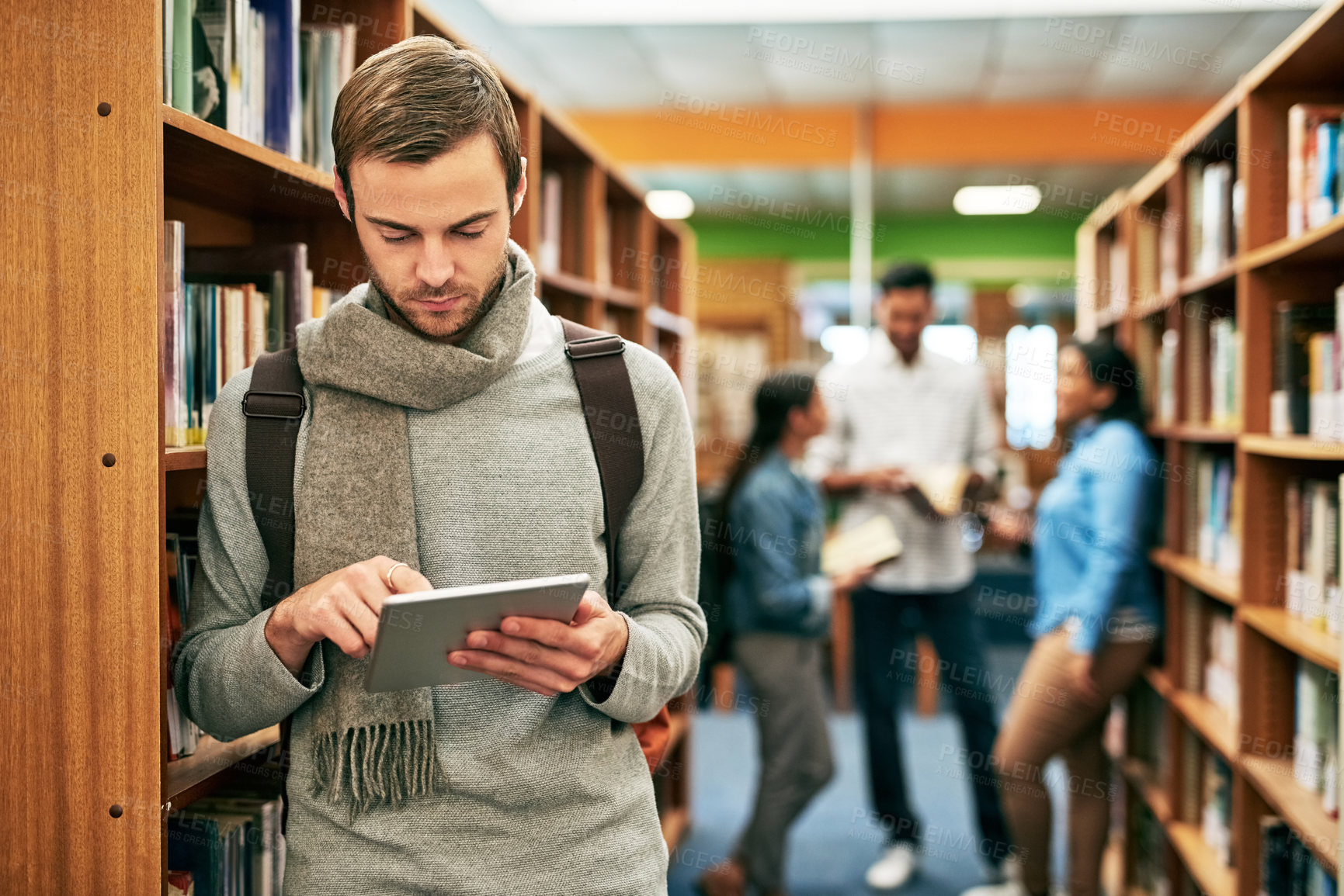 Buy stock photo Bookshelf, campus and man with tablet in library for social media, network or university update. Academy, person and student with internet on tech for education website, notification and information