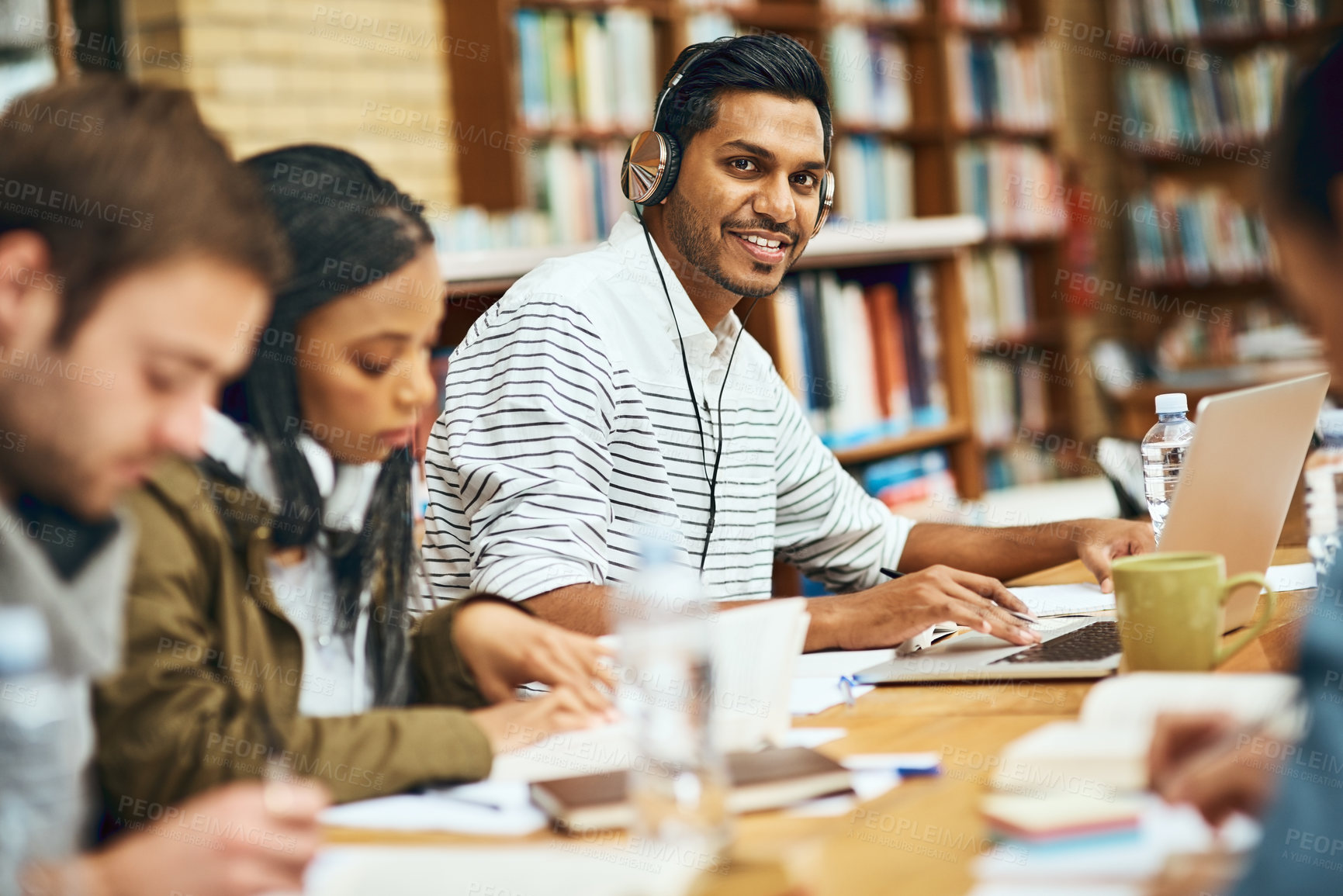 Buy stock photo Man, portrait and laptop in library for education, studying and headphones for music. Student, study group and smile at computer for knowledge, learning and exam preparation on university campus 