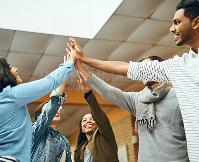 Buy stock photo Cropped shot of a group of university students high fiving while studying in the library