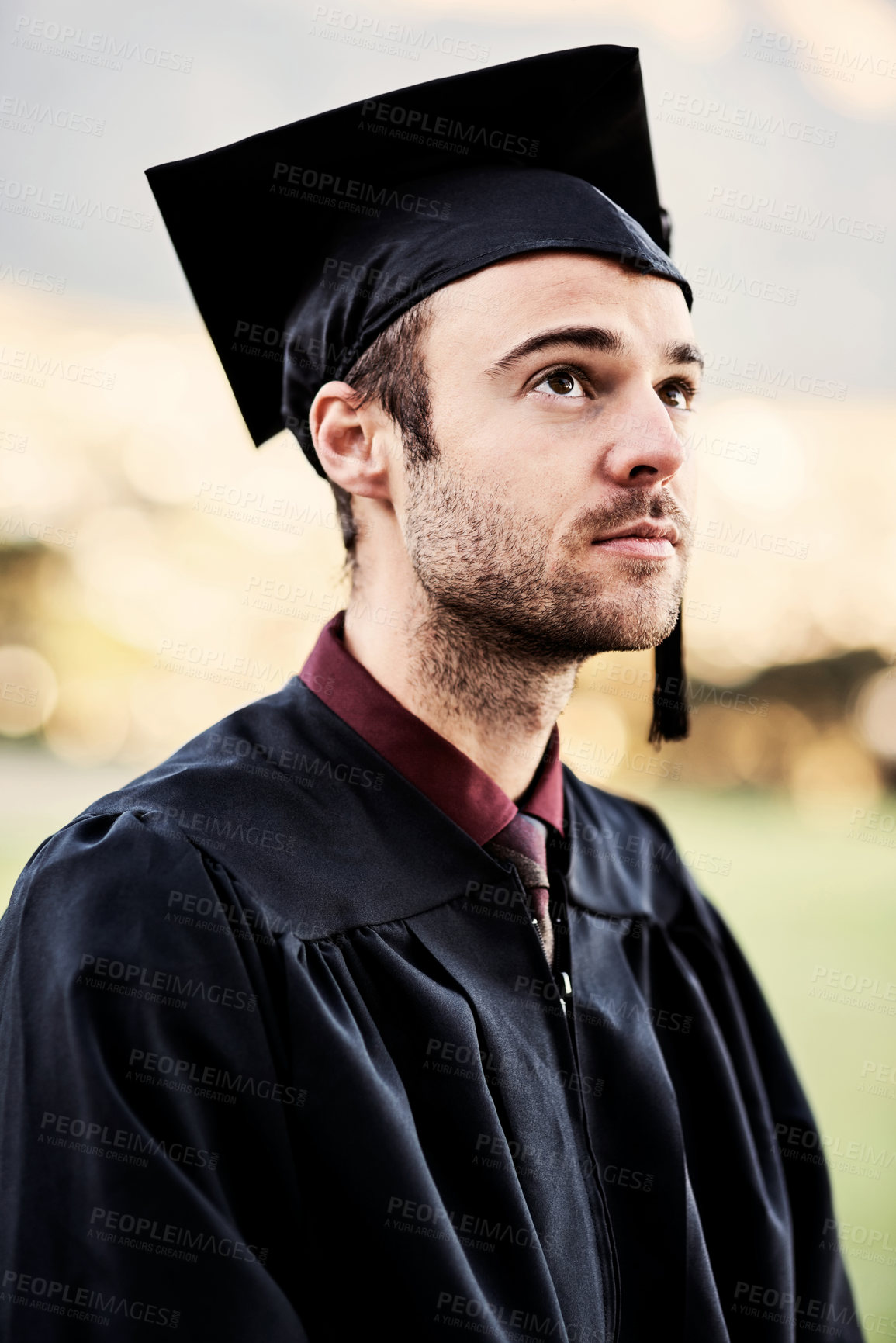 Buy stock photo Graduation, student and man outdoor at university for diploma ceremony, achievement and thinking of future. College graduate, bokeh or scholarship success with academic milestone or certificate event