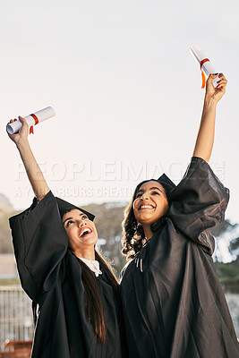 Buy stock photo Shot of two students celebrating with their diplomas on graduation day