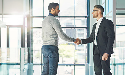 Buy stock photo Businessman standing, smiling and with a handshake, greets a colleague in an office. Executive meets client or partner and shakes hands. Two happy professionals agree on a successful business project
