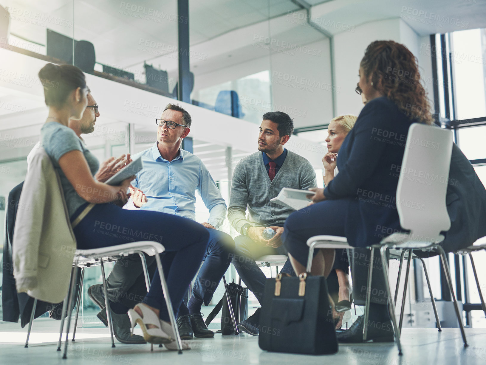 Buy stock photo Shot of a group of coworkers talking together while sitting in a circle in an office