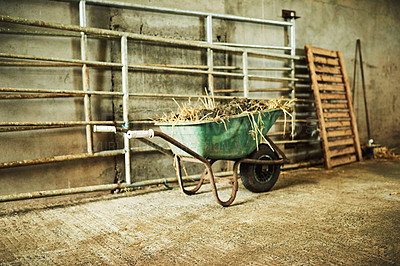 Buy stock photo Storage, farm and wheelbarrow with hay in barn for feed, fertilizer or dirt at rural small business. Agriculture, equipment or abandoned cart with compost, soil or manure in clean warehouse at ranch 