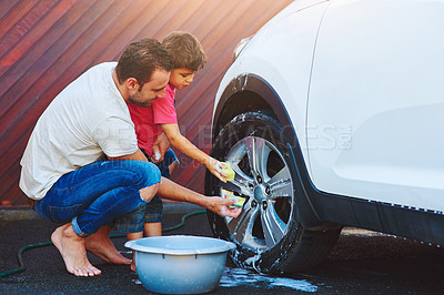 Buy stock photo Full length shot of a father and son washing the wheel of a car together