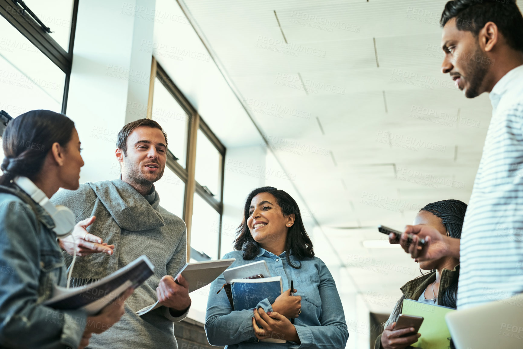 Buy stock photo Happy, group and students with education, textbooks and diversity in corridor for lecture or class. People, discussion and together for assignment, grades or project for study, learning or university