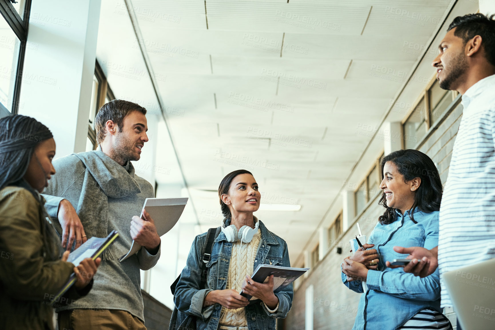 Buy stock photo Happy, group and students with education, discussion and diversity in corridor for lecture or class. People, textbooks and together for assignment, grades or project for study, learning or university