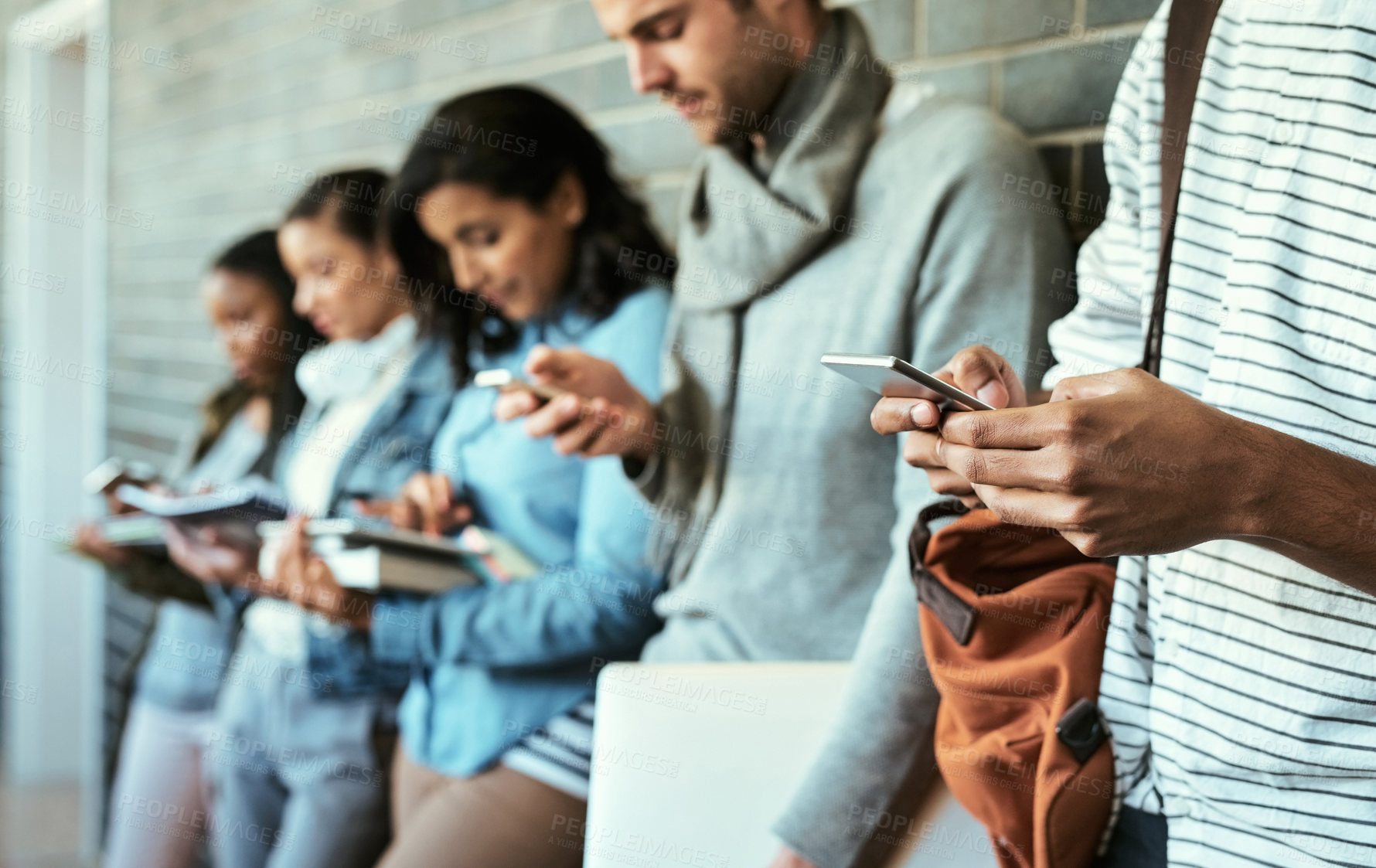 Buy stock photo Hands, group and student with technology, textbooks and diversity in corridor for lecture or class. People, connection and mobile for assignment, grades and project for study, learning and university