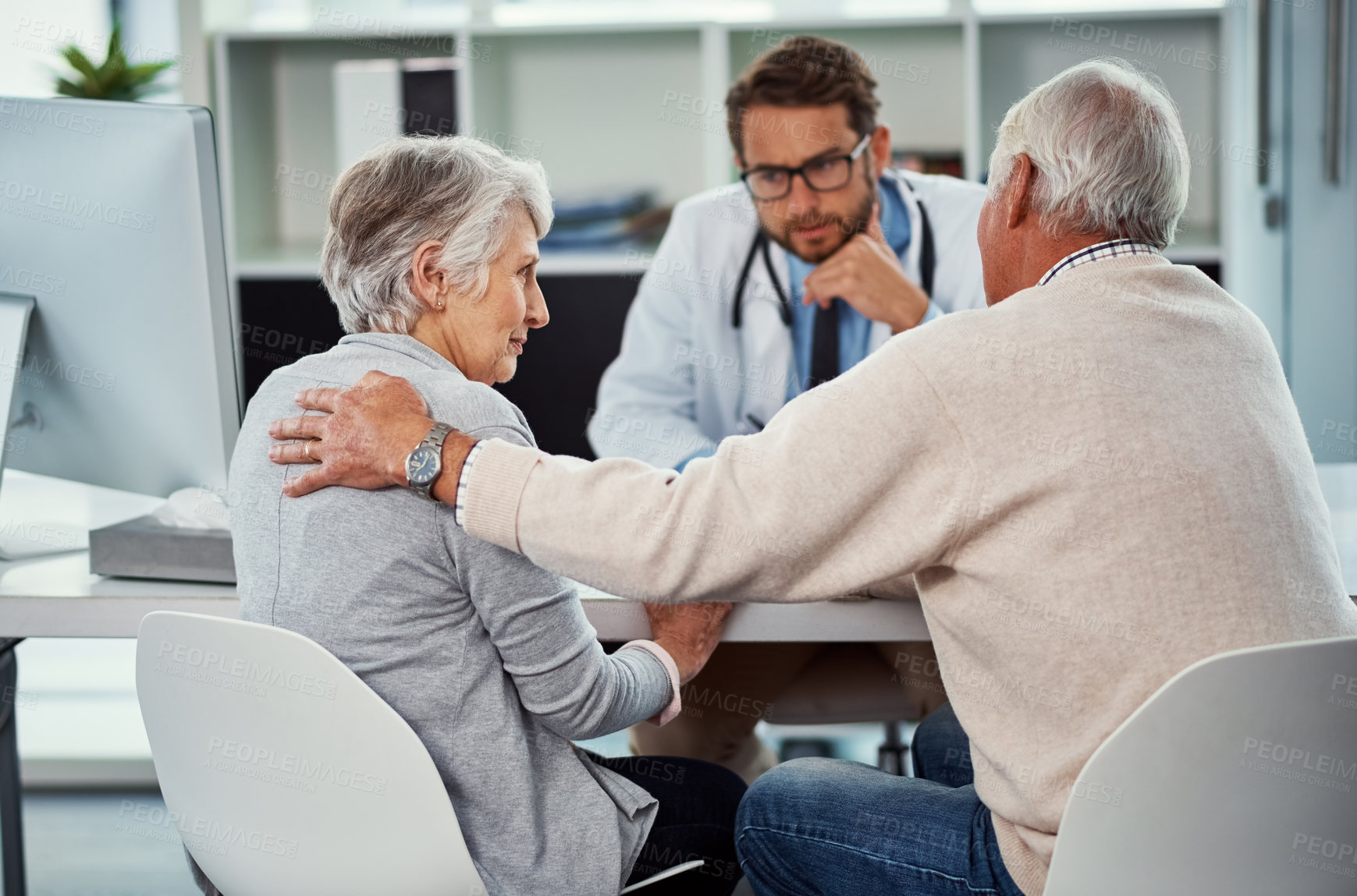 Buy stock photo Shot of a senior man consoling his wife during a consultation with a doctor in a clinic