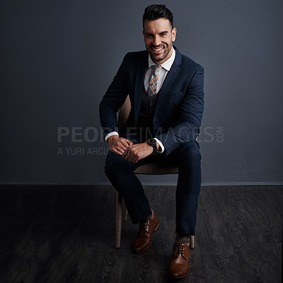 Buy stock photo Studio shot of a stylish young businessman sitting on a chair against a gray background