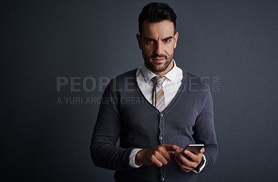 Buy stock photo Studio shot of a stylish young businessman using a mobile phone against a gray background
