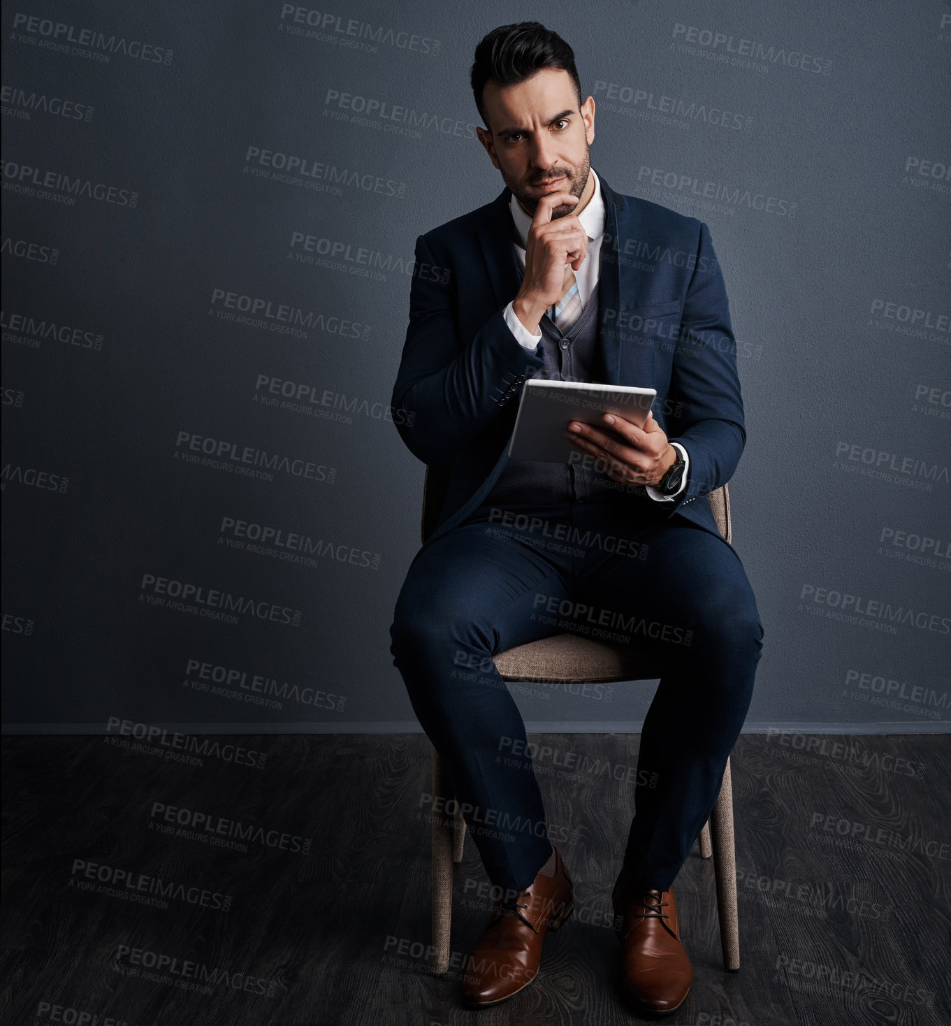 Buy stock photo Studio shot of a stylish young businessman using a digital tablet against a gray background