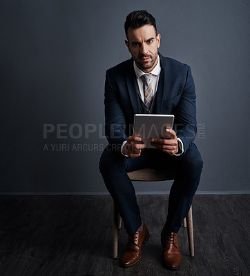 Buy stock photo Studio shot of a stylish young businessman using a digital tablet against a gray background