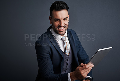 Buy stock photo Studio shot of a stylish young businessman using a digital tablet against a gray background