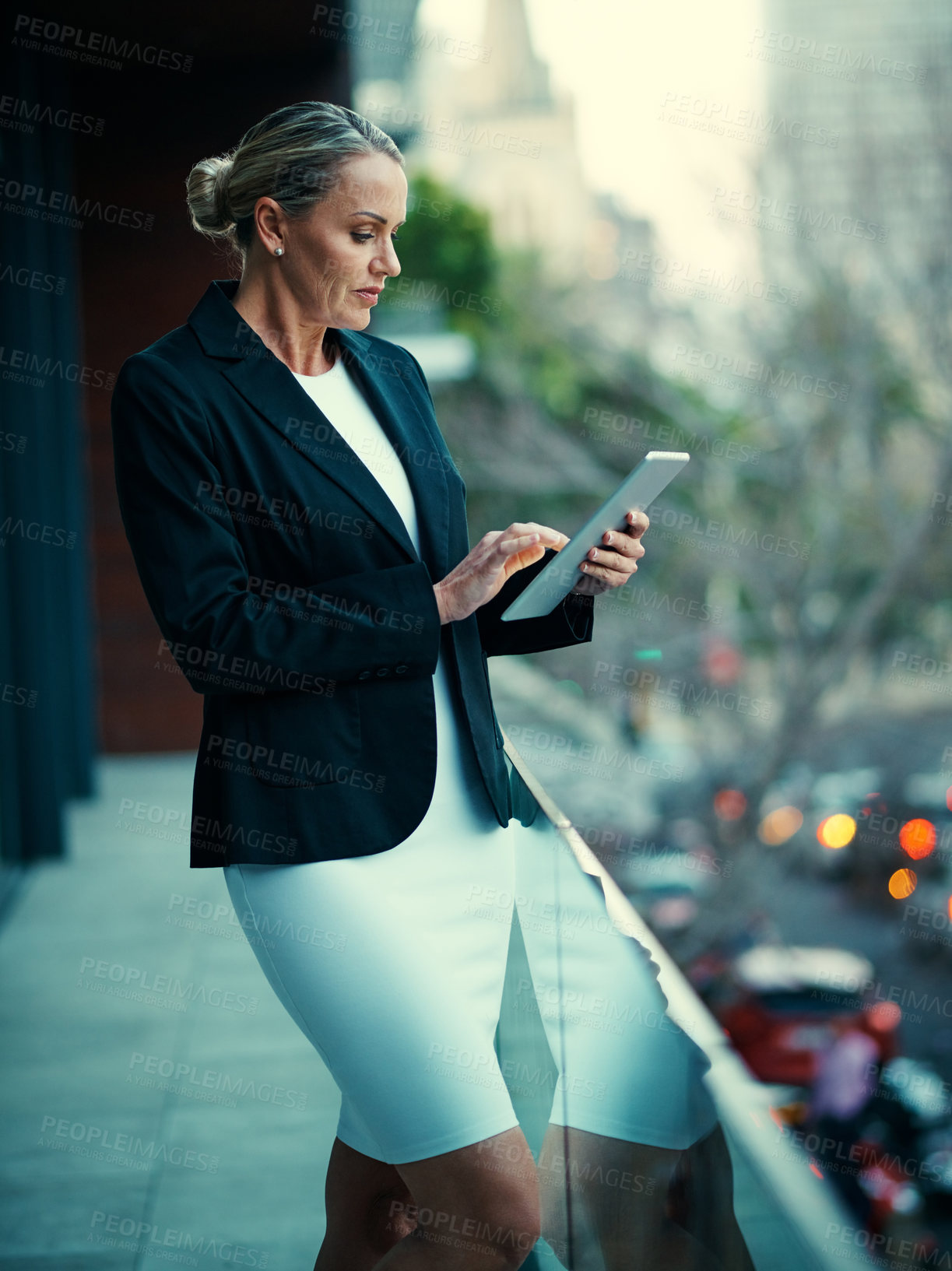 Buy stock photo Shot of a mature businesswoman standing outside on the balcony of an office and using a digital tablet