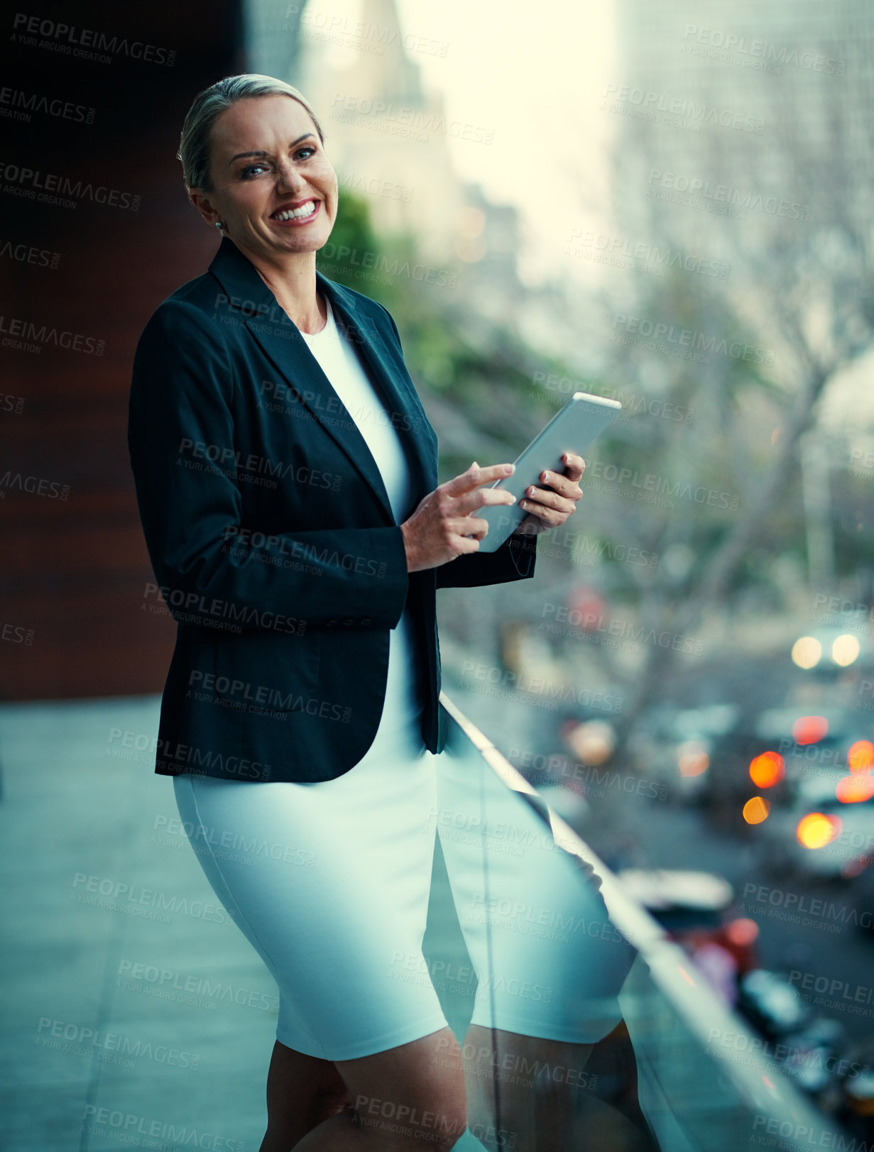 Buy stock photo Portrait of a mature businesswoman standing outside on the balcony of an office and using a digital tablet