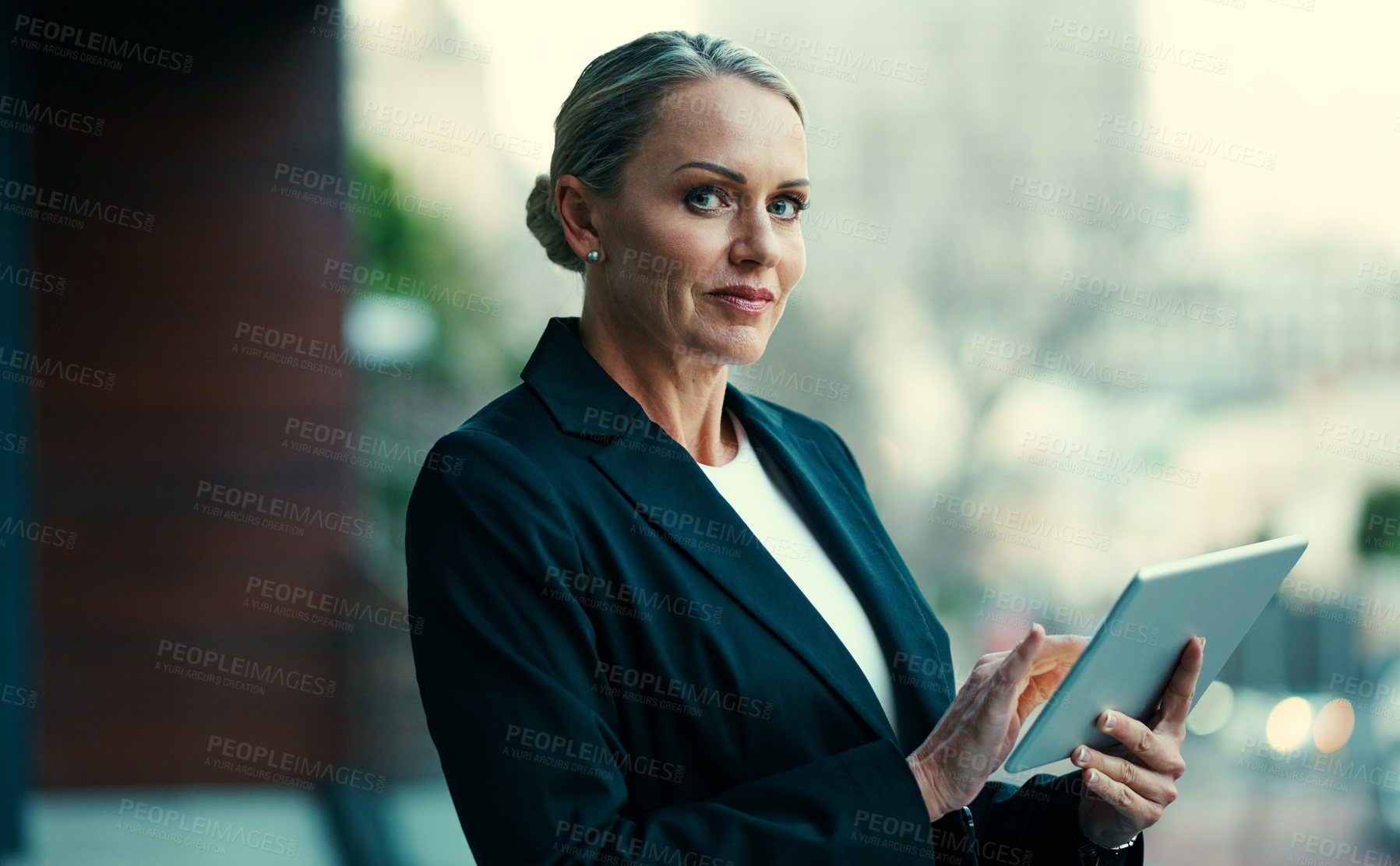Buy stock photo Portrait of a mature businesswoman standing outside on the balcony of an office and using a digital tablet