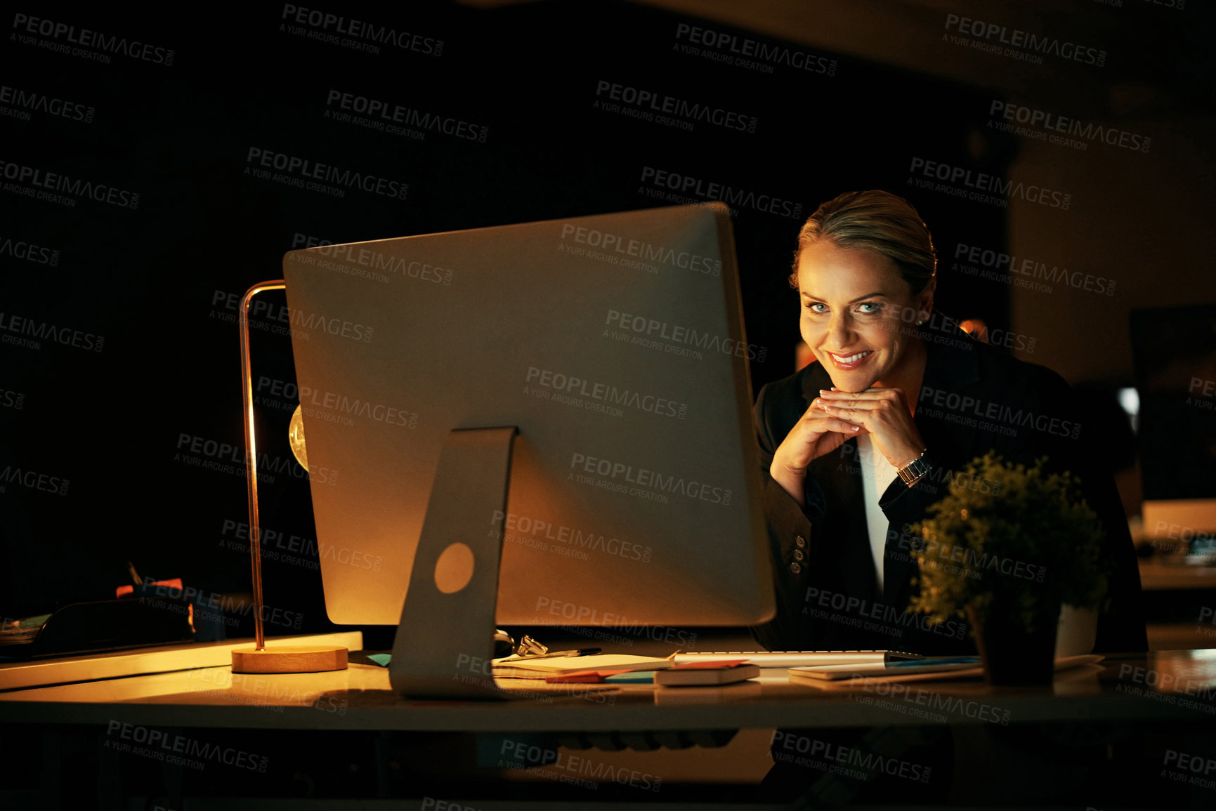 Buy stock photo Mature woman, computer and smile in office at night for review, project or notes at media company. Person, pc and journalist with pride, portrait and overtime for article at creative agency in Italy