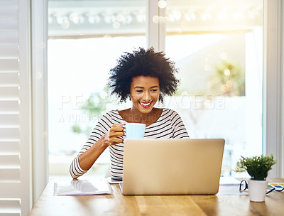Buy stock photo Shot of a focused young woman working on a laptop and drinking coffee at home