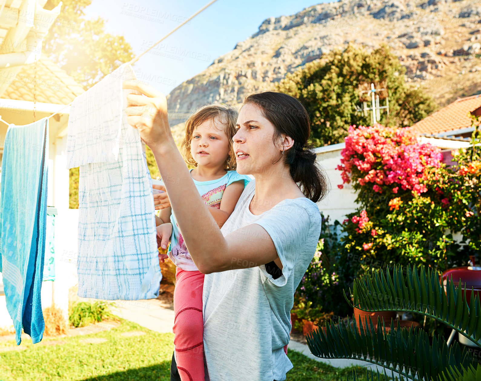 Buy stock photo Backyard, mother and child hanging laundry together with help, teaching and learning chores. Housekeeping, mom and daughter with clean clothes on line outside to sun dry with pegs, care and bonding.