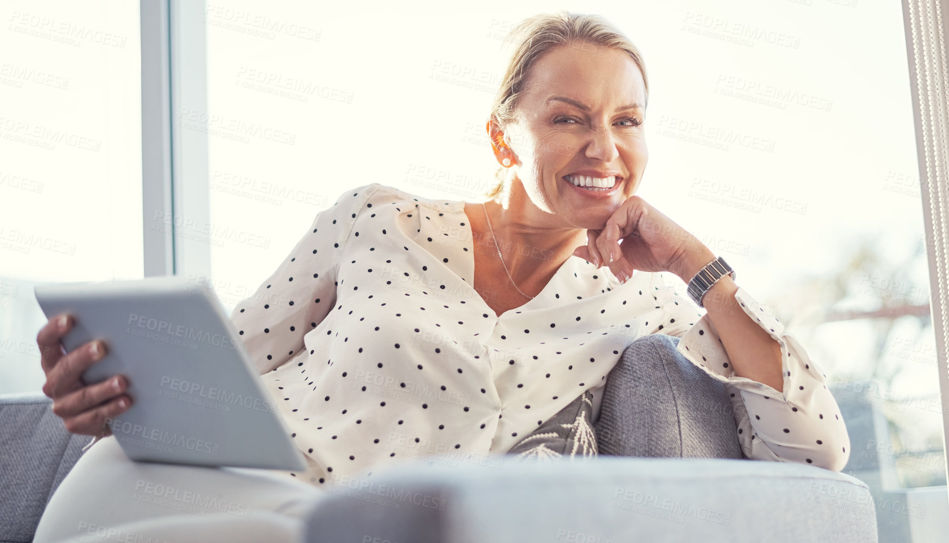 Buy stock photo Cropped shot of a mature woman using her digital tablet while relaxing at home