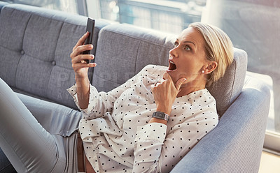 Buy stock photo Cropped shot of a mature woman using her cellphone while relaxing at home