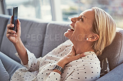 Buy stock photo Cropped shot of a mature woman using her cellphone while relaxing at home