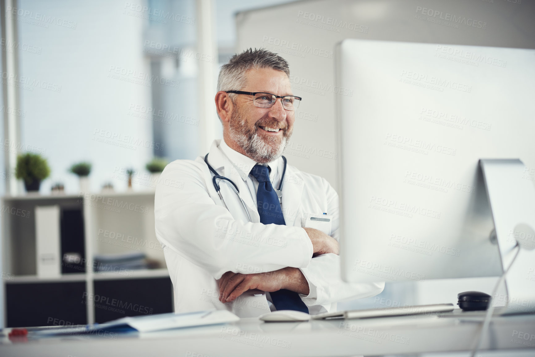 Buy stock photo Shot of a mature doctor using a computer at a desk in his office