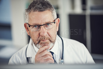 Buy stock photo Portrait of a mature doctor using a computer at a desk in his office